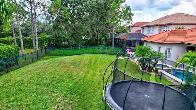 view of yard with a pool with connected hot tub, a fenced backyard, and a trampoline