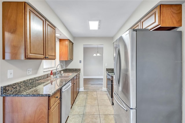 2961 Briar Cliff Dr, Palm Harbor, FL 34684 - kitchen with light tile patterned flooring, a sink, brown cabinetry, stainless steel appliances, and baseboards