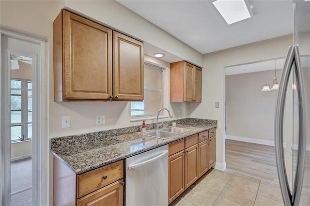 2961 Briar Cliff Dr, Palm Harbor, FL 34684 - kitchen featuring appliances with stainless steel finishes, a sink, dark stone counters, baseboards, and light tile patterned floors