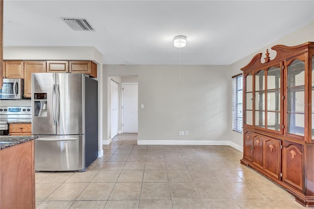 2961 Briar Cliff Dr, Palm Harbor, FL 34684 - kitchen featuring dark stone counters, stainless steel appliances, baseboards, light tile patterned floors, and visible vents