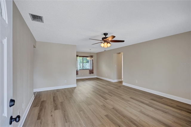 2961 Briar Cliff Dr, Palm Harbor, FL 34684 - spare room with a textured ceiling, visible vents, baseboards, ceiling fan with notable chandelier, and light wood-style flooring