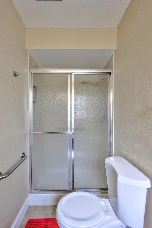 2961 Briar Cliff Dr, Palm Harbor, FL 34684 - bathroom with a textured wall, toilet, tile patterned floors, baseboards, and a shower stall