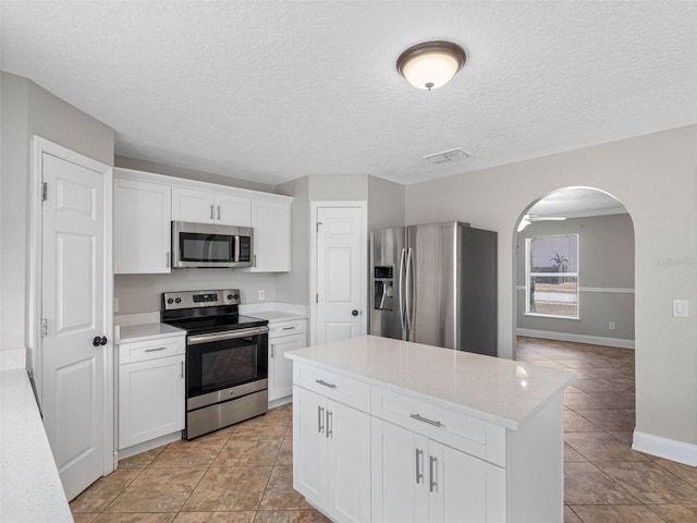 kitchen with visible vents, arched walkways, light countertops, and stainless steel appliances