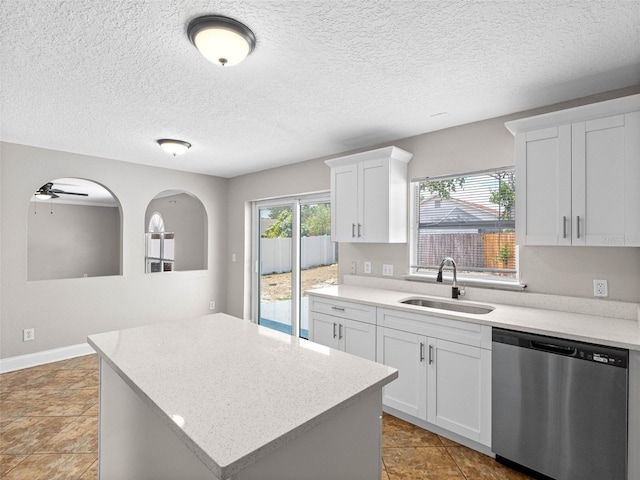kitchen featuring stainless steel dishwasher, a kitchen island, ceiling fan, white cabinets, and a sink