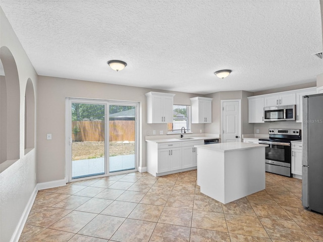 kitchen featuring plenty of natural light, appliances with stainless steel finishes, light countertops, baseboards, and a sink