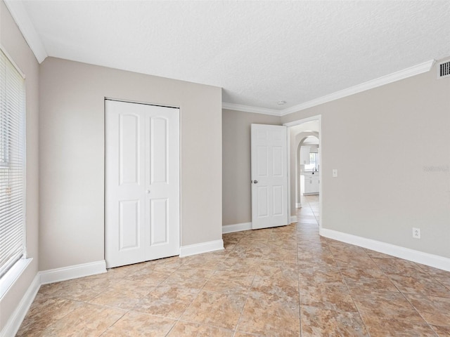 unfurnished bedroom featuring arched walkways, visible vents, multiple windows, and a closet