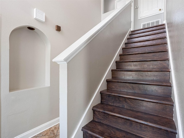stairs with visible vents, arched walkways, and baseboards
