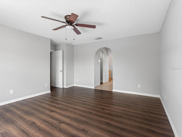 unfurnished room with arched walkways, a ceiling fan, wood finished floors, and visible vents
