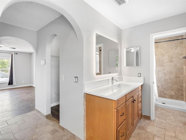 full bathroom featuring stone tile floors, visible vents, a shower stall, and vanity