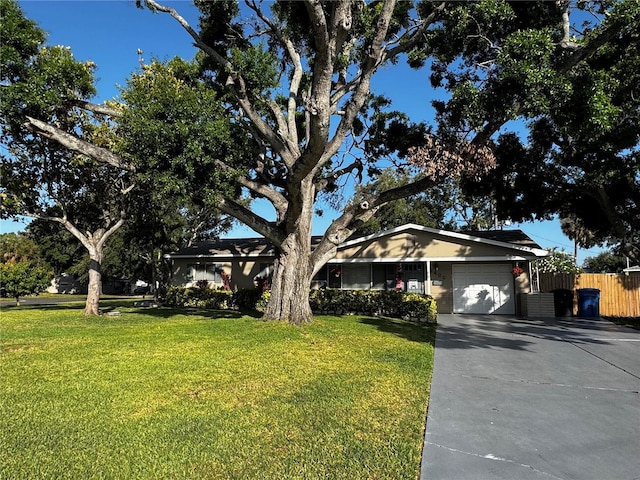 ranch-style house with an attached garage, fence, a front yard, and concrete driveway