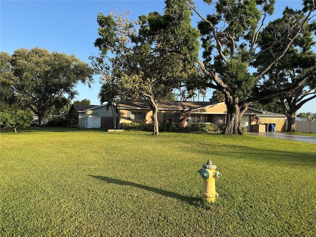 view of yard with a garage, fence, and driveway