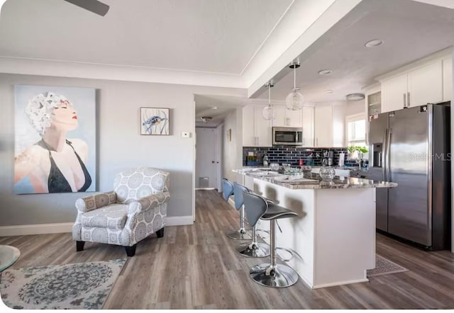 kitchen featuring appliances with stainless steel finishes, a kitchen bar, and dark wood-type flooring