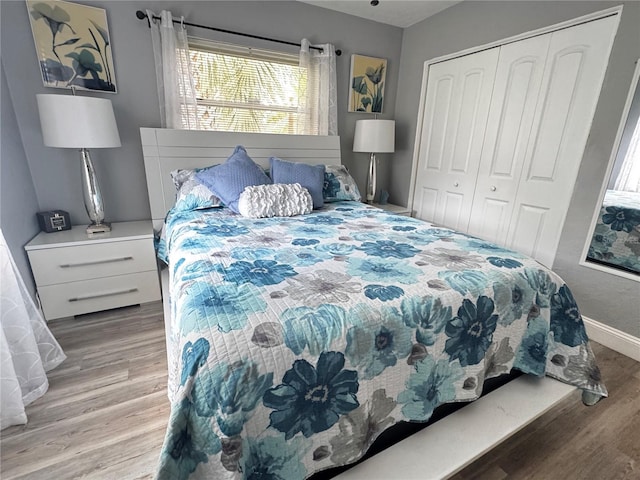 bedroom featuring baseboards, multiple windows, a closet, and wood finished floors