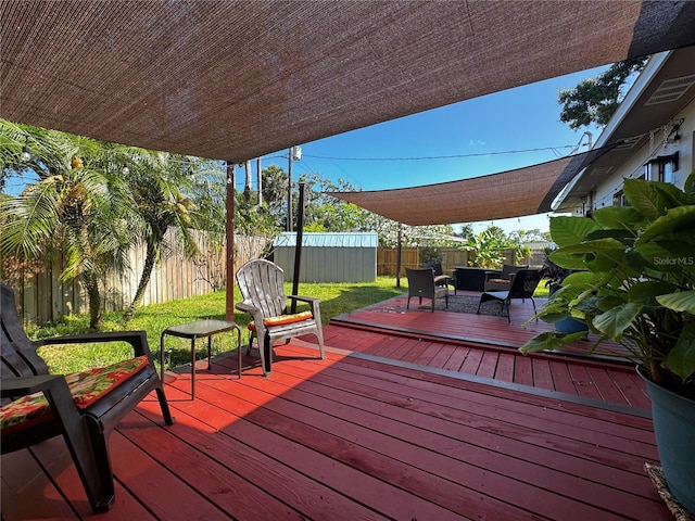 wooden terrace with a fenced backyard, a storage unit, and an outdoor structure