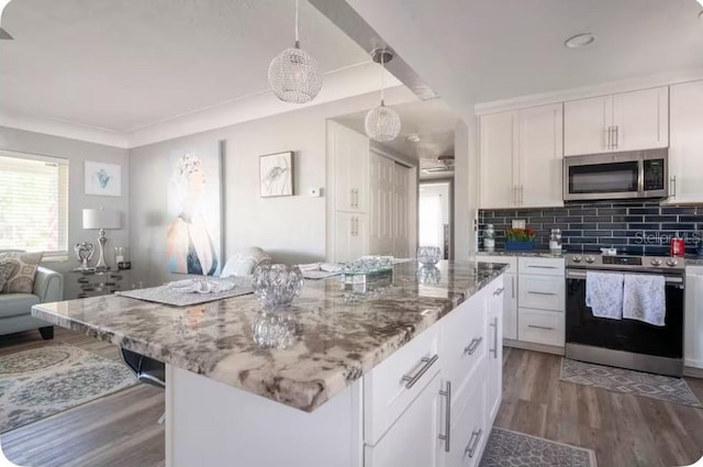 kitchen with wood finished floors, light stone countertops, white cabinets, backsplash, and stainless steel appliances