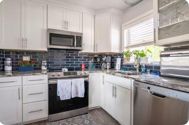 kitchen with white cabinetry, appliances with stainless steel finishes, light stone countertops, and tasteful backsplash