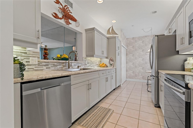 7 Island Park Pl Unit 204, Dunedin, FL 34698 - kitchen with appliances with stainless steel finishes, wallpapered walls, a sink, baseboards, and decorative backsplash
