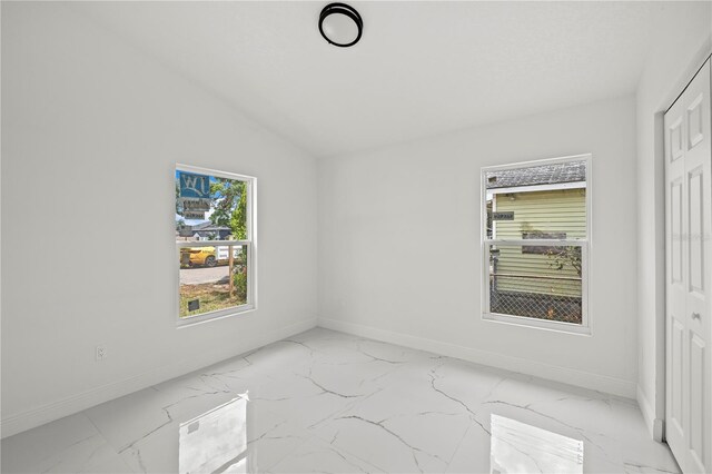 3803 E Curtis St, Tampa, FL 33610 - unfurnished bedroom featuring light marble finish floors, baseboards, a closet, and vaulted ceiling