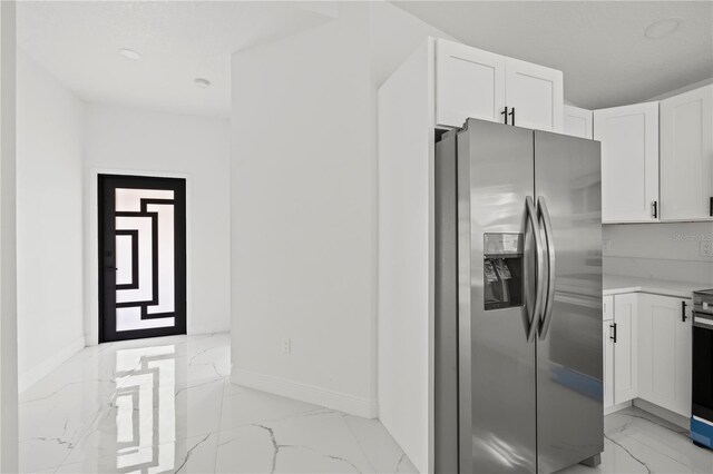 3803 E Curtis St, Tampa, FL 33610 - kitchen with stainless steel fridge, light marble finish floors, white cabinetry, light countertops, and baseboards