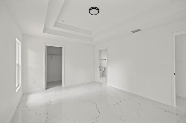 3803 E Curtis St, Tampa, FL 33610 - unfurnished bedroom with baseboards, light marble finish floors, a walk in closet, connected bathroom, and a closet