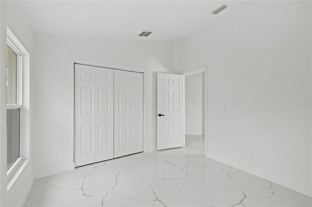 3803 E Curtis St, Tampa, FL 33610 - unfurnished bedroom with marble finish floors, baseboards, a closet, and multiple windows