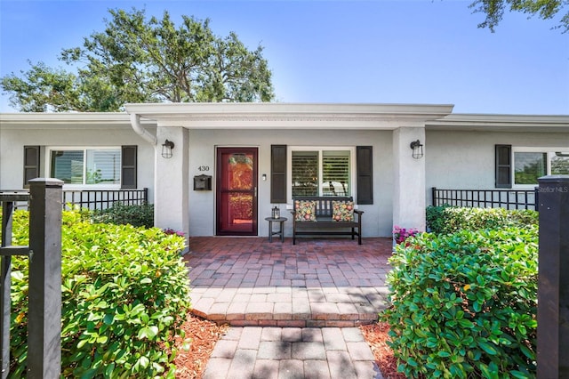 entrance to property featuring covered porch and stucco siding