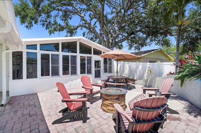 view of patio / terrace with fence, a sunroom, and an outdoor fire pit