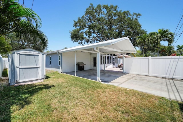 rear view of house with a lawn, a shed, a fenced backyard, and a patio area