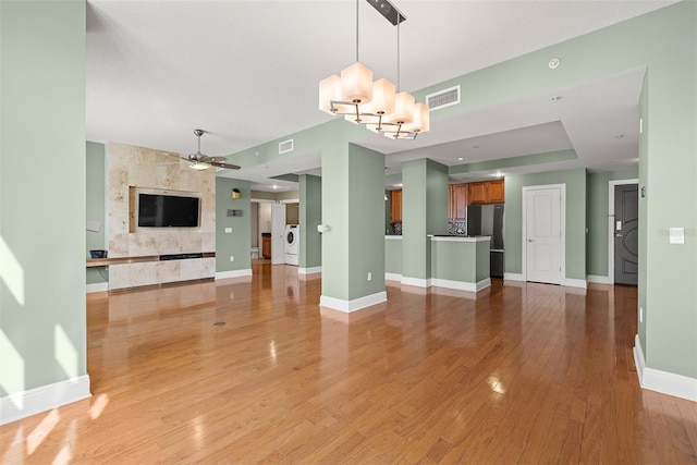 1227 E Madison St Unit 902, Tampa, FL 33602 - unfurnished living room featuring a ceiling fan, light wood-style floors, a chandelier, baseboards, and a tiled fireplace
