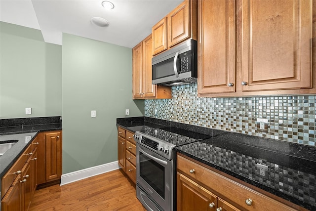 1227 E Madison St Unit 902, Tampa, FL 33602 - kitchen featuring stainless steel appliances, light wood-style flooring, decorative backsplash, and dark stone countertops