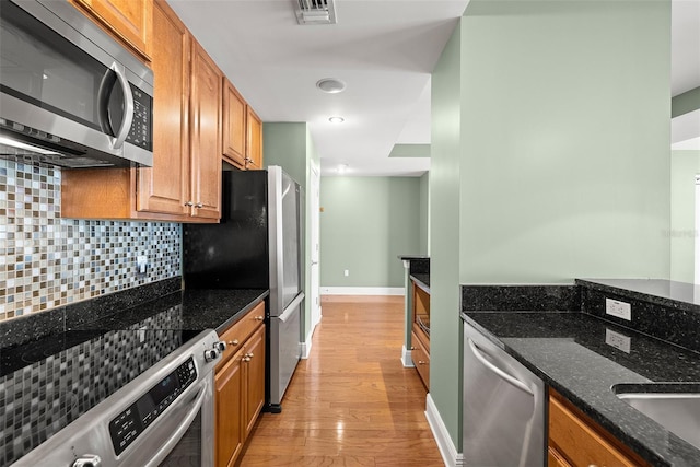 1227 E Madison St Unit 902, Tampa, FL 33602 - kitchen with appliances with stainless steel finishes, decorative backsplash, light wood finished floors, brown cabinets, and recessed lighting