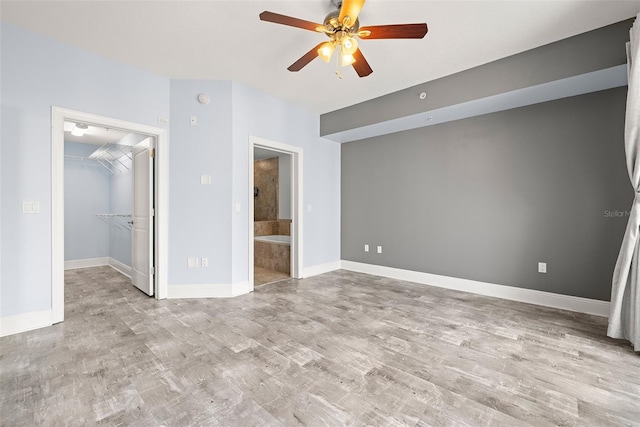 1227 E Madison St Unit 902, Tampa, FL 33602 - unfurnished bedroom with a walk in closet, wood finished floors, ensuite bathroom, baseboards, and a ceiling fan