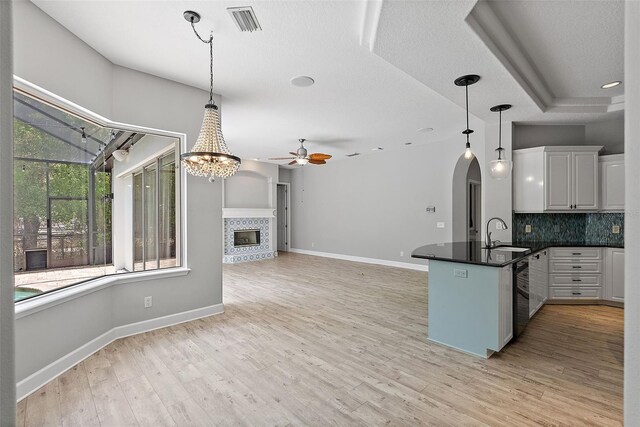 7314 Hunt Club Ln, Seminole, FL 33776 - kitchen with a peninsula, dark countertops, a ceiling fan, a tile fireplace, and backsplash