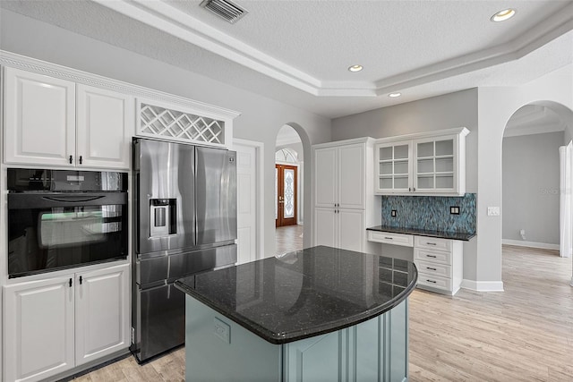 7314 Hunt Club Ln, Seminole, FL 33776 - kitchen with stainless steel fridge with ice dispenser, arched walkways, oven, a raised ceiling, and white cabinetry