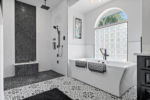 7314 Hunt Club Ln, Seminole, FL 33776 - bathroom featuring a freestanding bath, wainscoting, a walk in shower, and tile patterned flooring