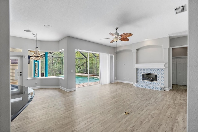 7314 Hunt Club Ln, Seminole, FL 33776 - unfurnished living room with ceiling fan, wood finished floors, baseboards, a tiled fireplace, and a textured ceiling