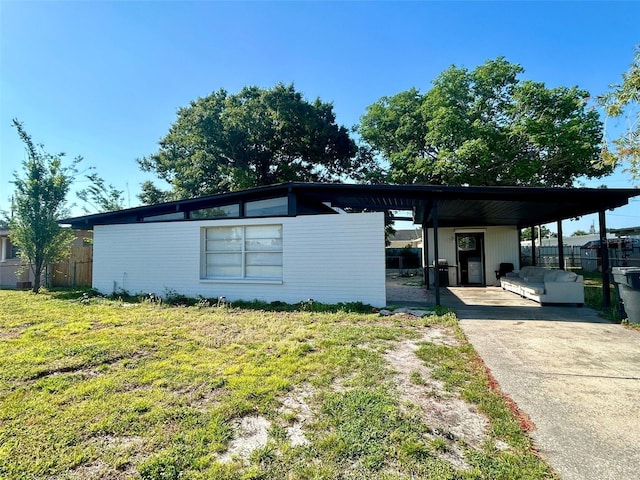 exterior space with fence, a carport, a yard, and driveway