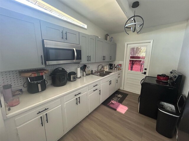 kitchen featuring light countertops, stainless steel microwave, tasteful backsplash, a sink, and range