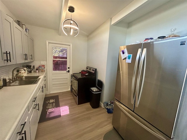 kitchen featuring backsplash, electric range, a sink, freestanding refrigerator, and light wood-style flooring