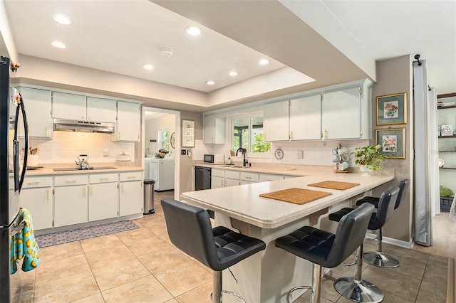 kitchen with washer and dryer, a sink, white microwave, light countertops, and recessed lighting