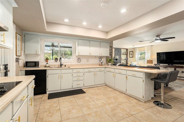 kitchen with a sink, black appliances, decorative backsplash, open floor plan, and recessed lighting