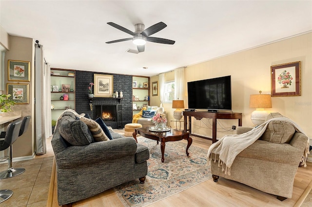 living area with a ceiling fan and a brick fireplace