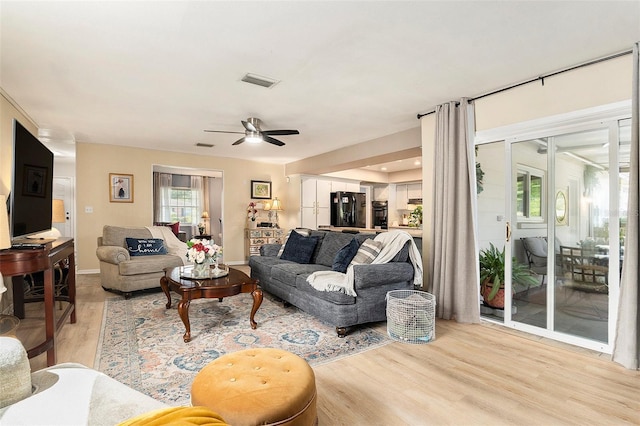 living area featuring light wood-style floors, a ceiling fan, and baseboards