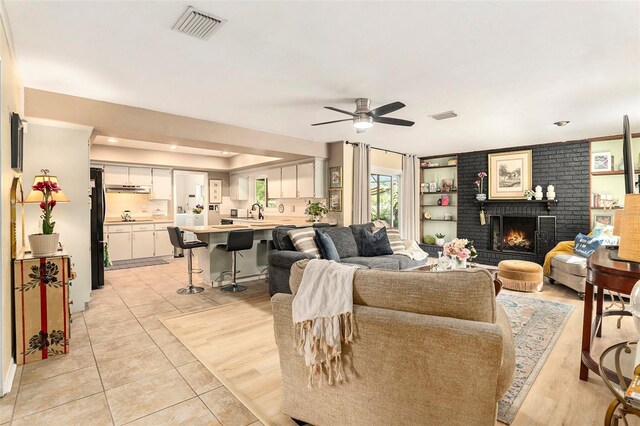 living area with a ceiling fan, a fireplace, and light tile patterned flooring