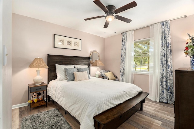 bedroom featuring wood finished floors, baseboards, and a ceiling fan