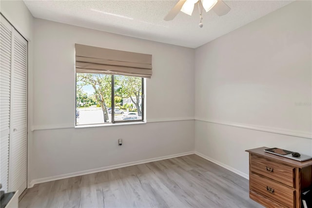 112 W Cypress Ct, Oldsmar, FL 34677 - unfurnished bedroom with a ceiling fan, a textured ceiling, baseboards, a closet, and light wood-style floors