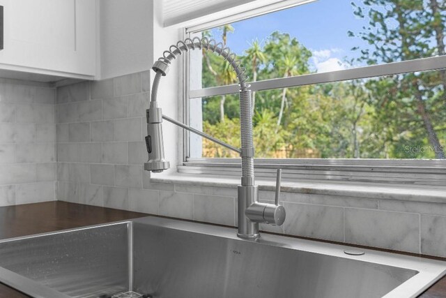 details with a sink, white cabinetry, and decorative backsplash
