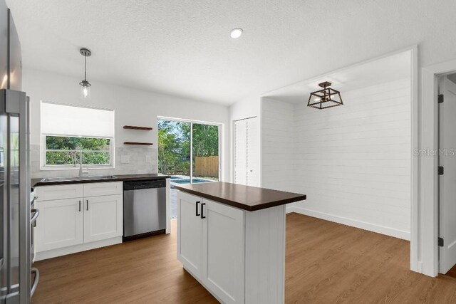 kitchen with wood finished floors, white cabinetry, a sink, and dishwasher