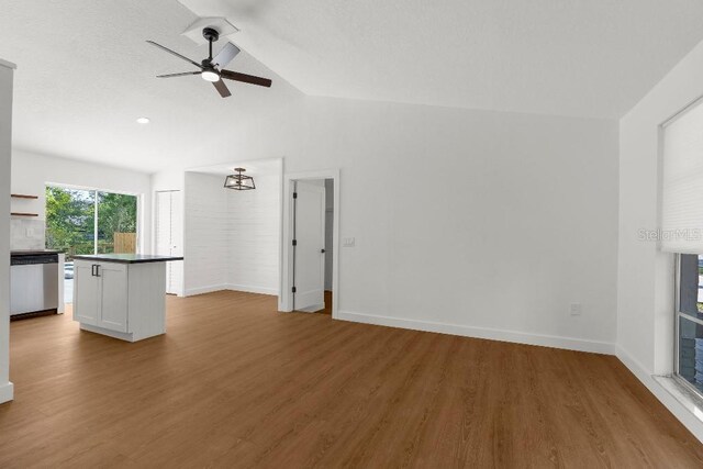 unfurnished living room with a ceiling fan, baseboards, vaulted ceiling, and wood finished floors