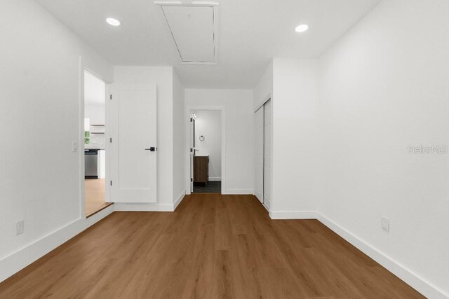 spare room featuring baseboards, attic access, wood finished floors, and recessed lighting